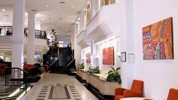 A spacious lobby with a central staircase, seating areas, and artwork on the walls.