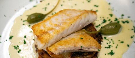A dish with fish and greens on a plate.