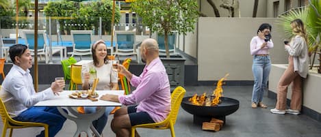 Un grupo de personas cenando al aire libre en una mesa con una chimenea.