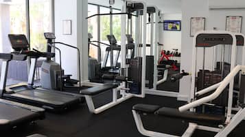 A gym with treadmills, weight machines, and a mirrored wall.