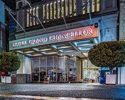 The exterior of Hotel Grand Chancellor with a prominent entrance, large windows, and a well-lit facade.