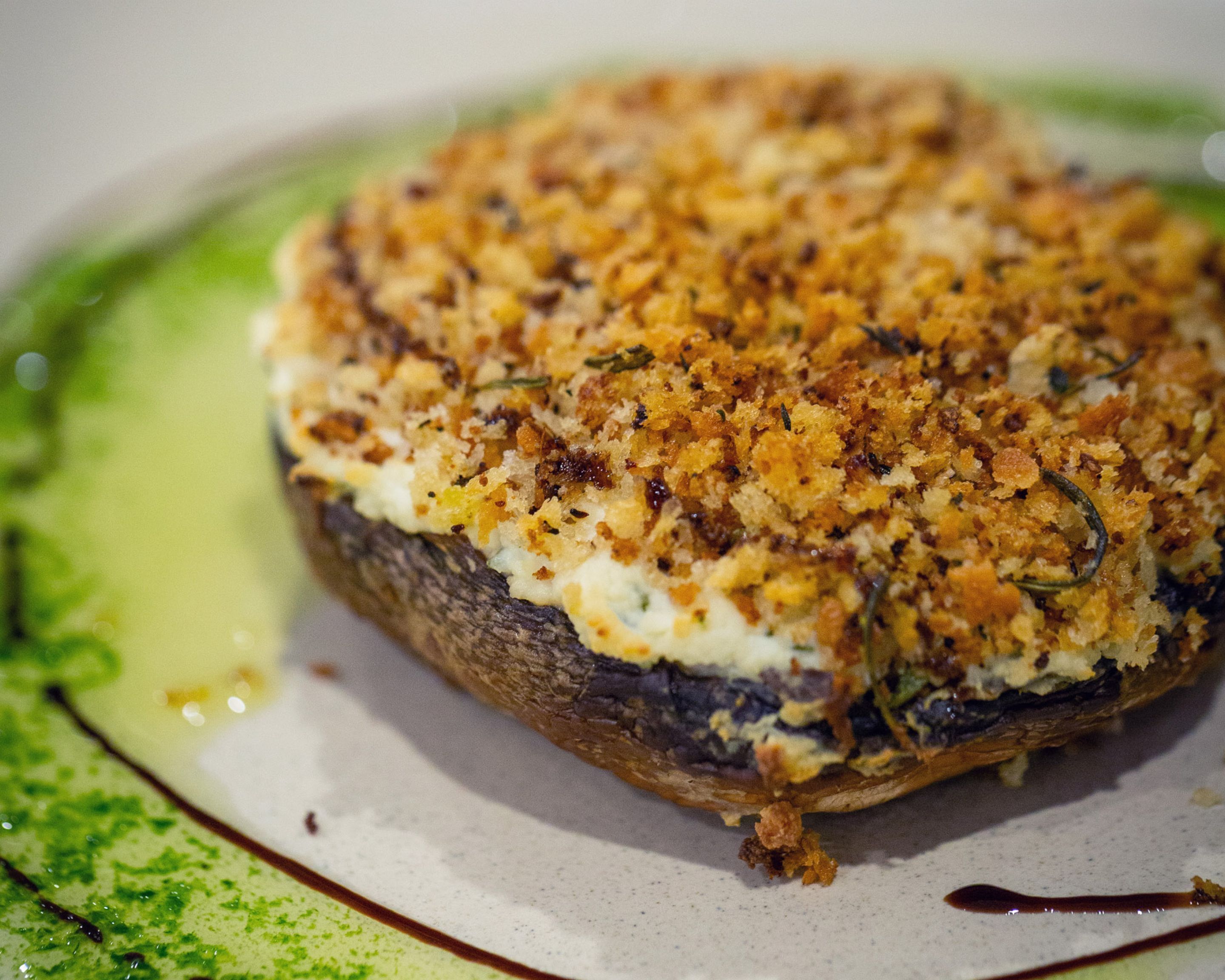 A close-up of a baked dish with a golden-brown crust, possibly a savory pastry or casserole, on a plate with a green rim.