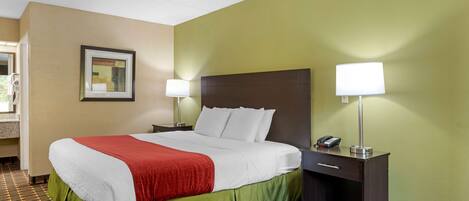 A hotel room with a bed, two bedside lamps, a nightstand with a phone, and a framed picture on the wall.