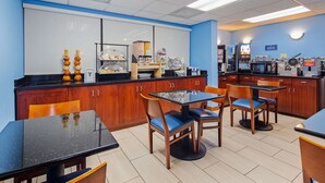 A clean, well-lit cafe with wooden furniture, a self-service food station, and a coffee machine.