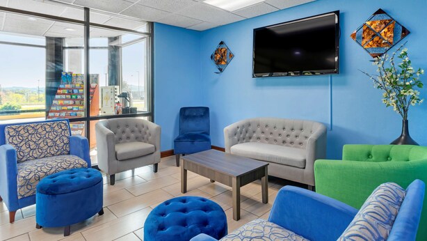 A modern lounge area with a large TV, comfortable seating, and a view through the glass wall.