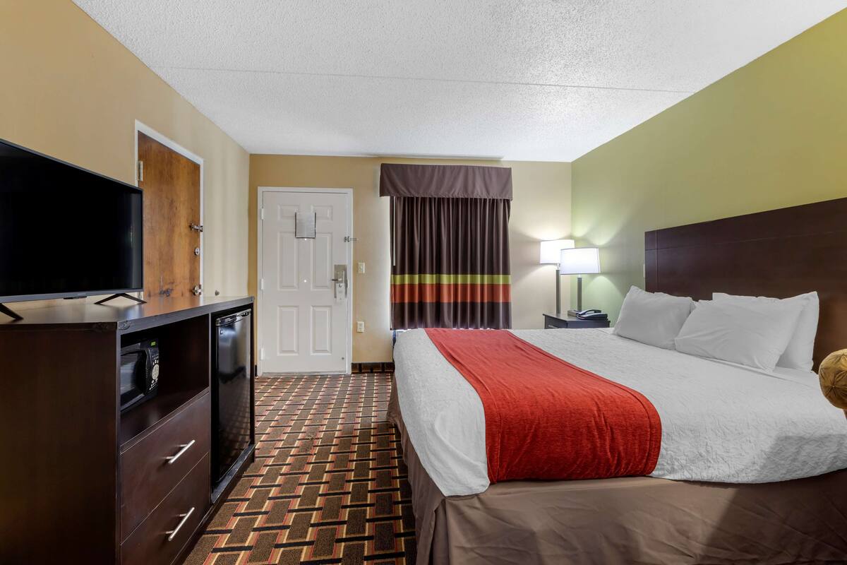 Una camera d'albergo con un letto, una televisione, una scrivania e una lampada.