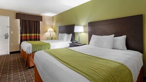 A hotel room with two beds, a door, a window with curtains, and a nightstand with a lamp.