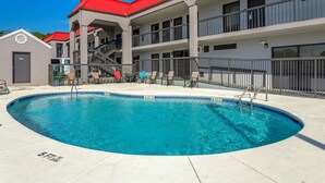 A swimming pool with a red-roofed building in the background.