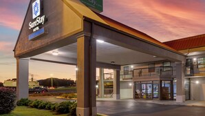 A SureStay hotel with a covered parking area, multiple floors, and a view of the surrounding landscape.