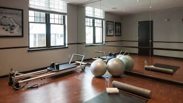 Ein Pilates-Studio mit Geräten, einem großen Spiegel und Fenstern.
