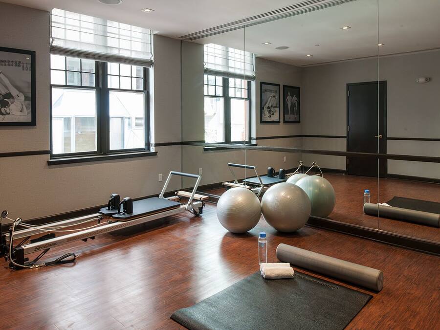 Ein Pilates-Studio mit Geräten, einem großen Spiegel und Fenstern.