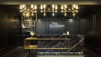 A reception desk with a marble top and a sign reading "The Goodwin Hartford's boutique hotel".