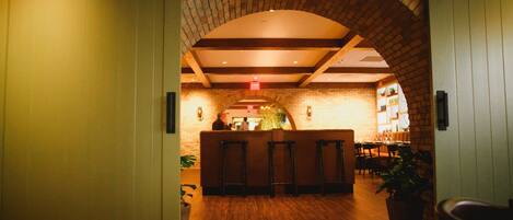 A lobby with a brick archway, wooden flooring, and a reception desk.