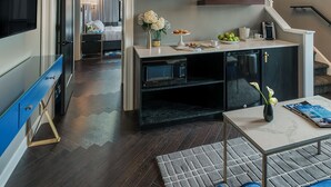 A modern living room with a staircase leading to a bedroom. The room features a flat-screen TV, a coffee table, and a sofa. - The Goodwin Hotel (Hartford)