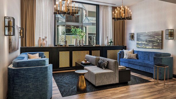 A modern living room with a large window, two sofas, a coffee table, and decorative items. - The Goodwin Hotel (Hartford)