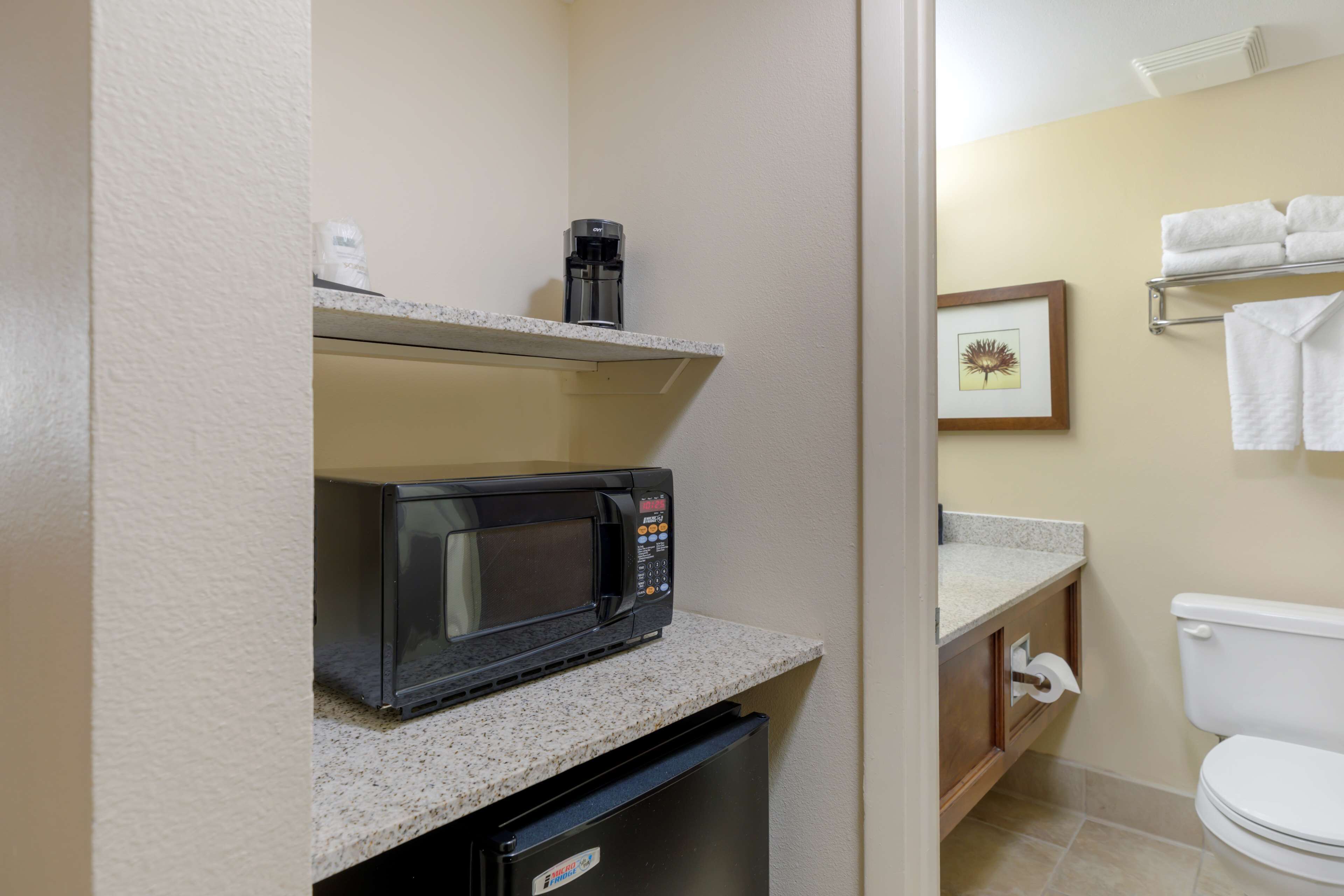 A compact kitchenette with a microwave, coffee maker, and a small refrigerator.