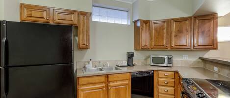 A kitchen with wooden cabinets, a black refrigerator, a microwave, a dishwasher, and a stove.
