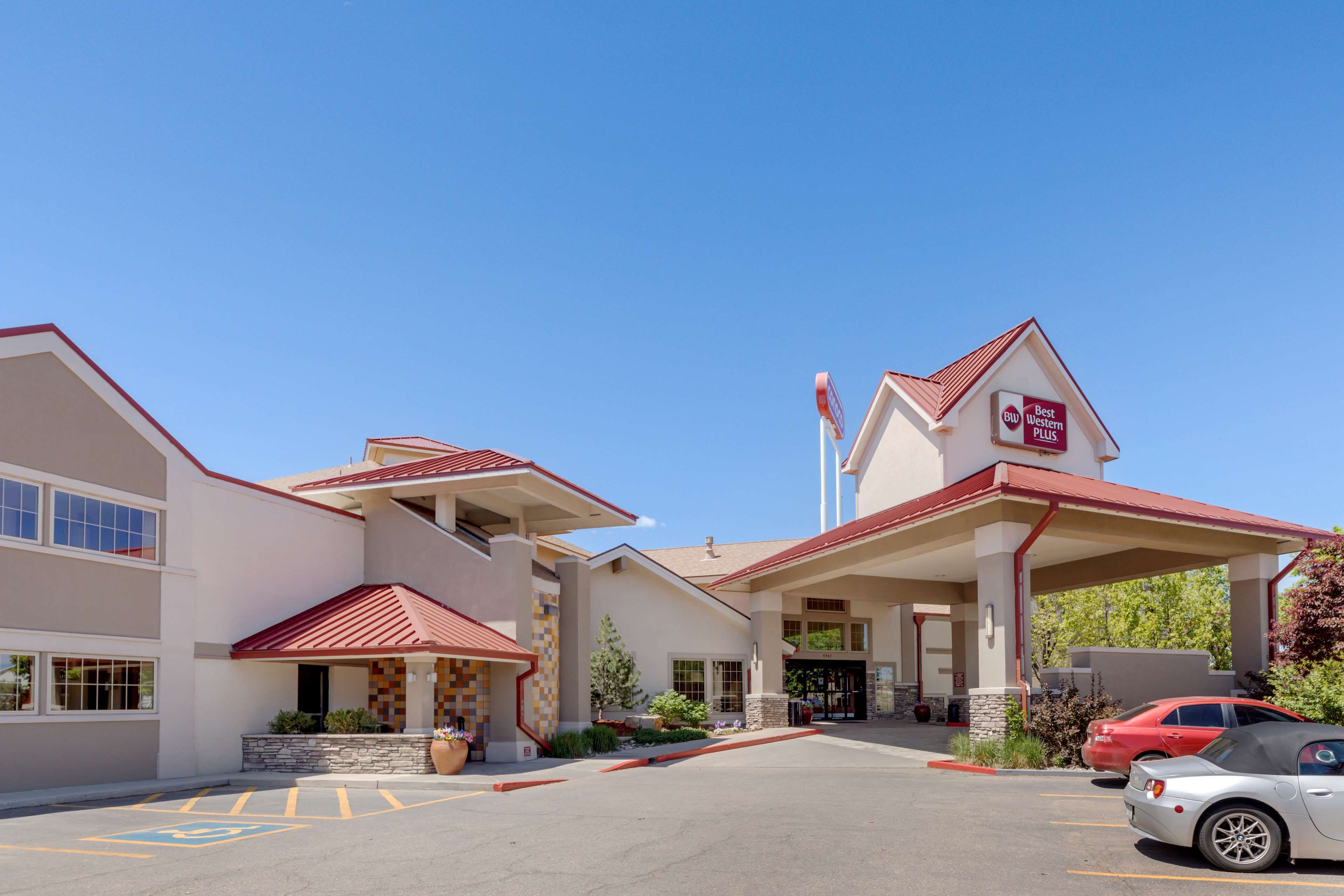 A hotel with a red roof, a Best Western Plus sign, and a parking lot with a few cars.