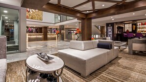 Una hall moderna di un albergo con reception, area salotto e bar.