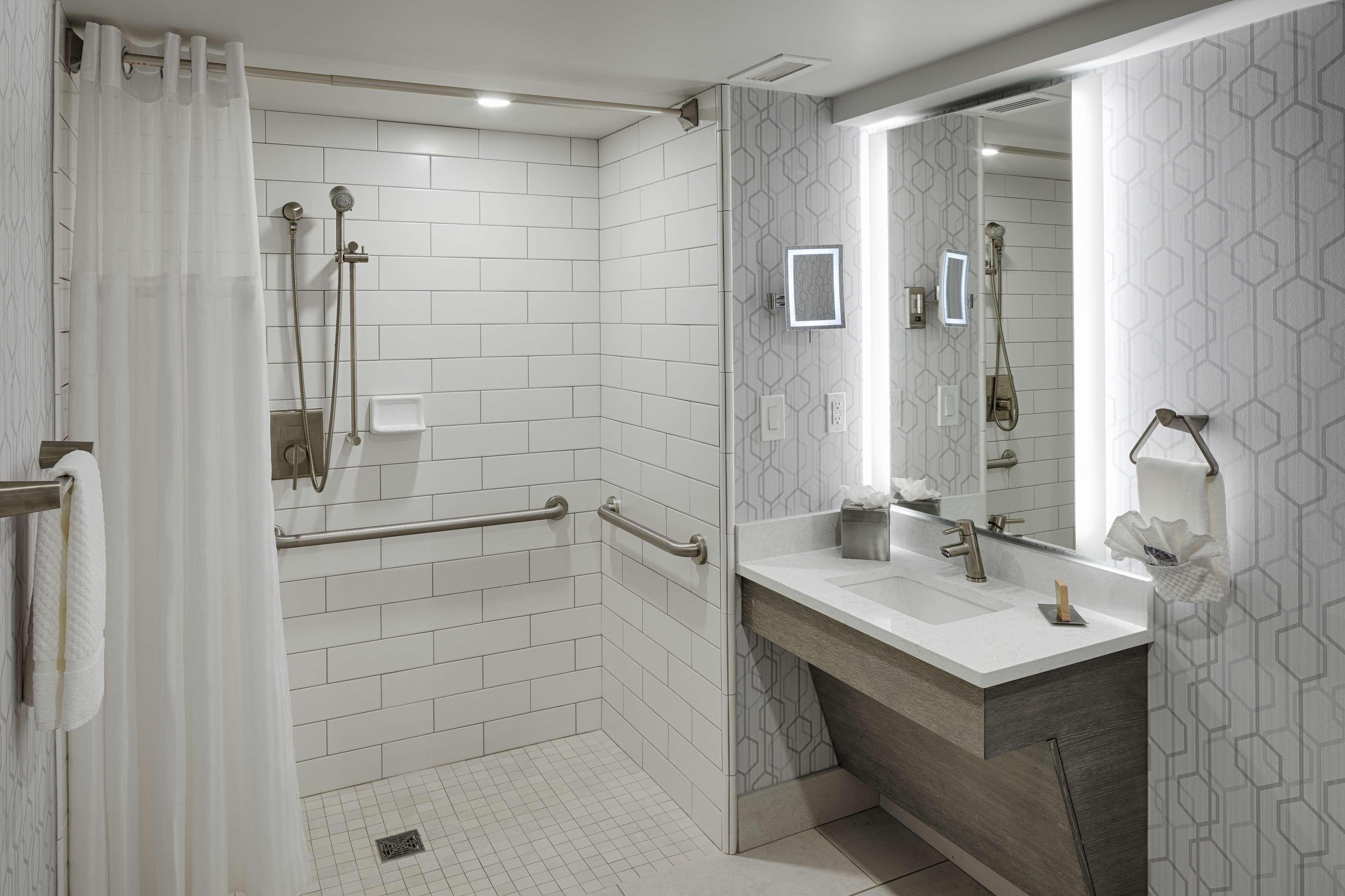 Un baño moderno con ducha, tocador con espejo y retrete.