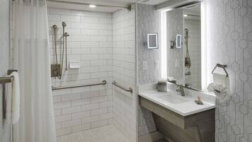A modern bathroom with a shower, a vanity with a mirror, and a toilet.