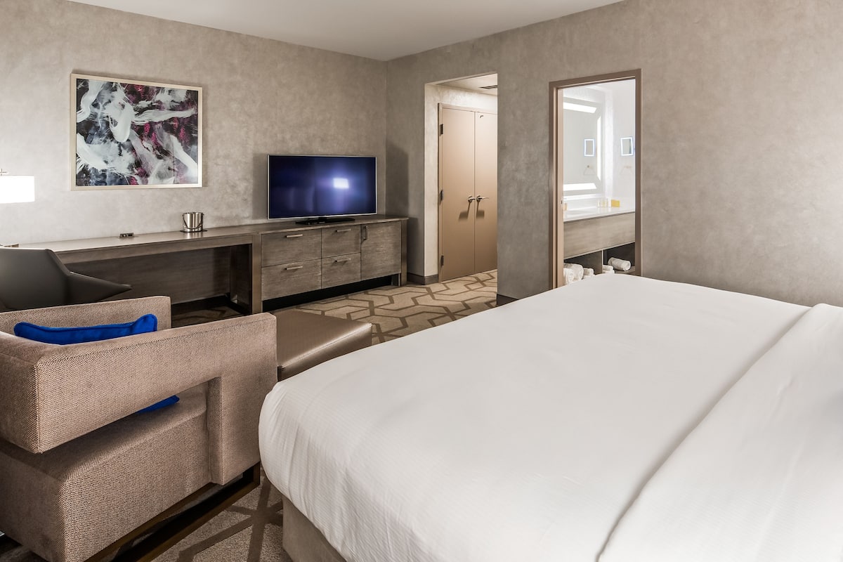 A hotel room with a bed, a TV, a desk, and a chair.