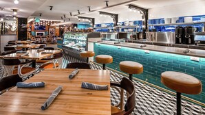 Un ristorante con un’area bar, tavoli con sedie e un bancone con attrezzature da cucina.
