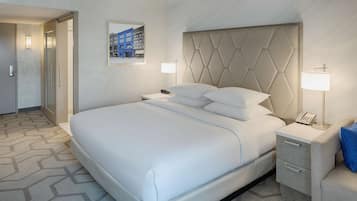 Une chambre d’hôtel avec un grand lit, une table de chevet avec une lampe et un tableau encadré au mur.