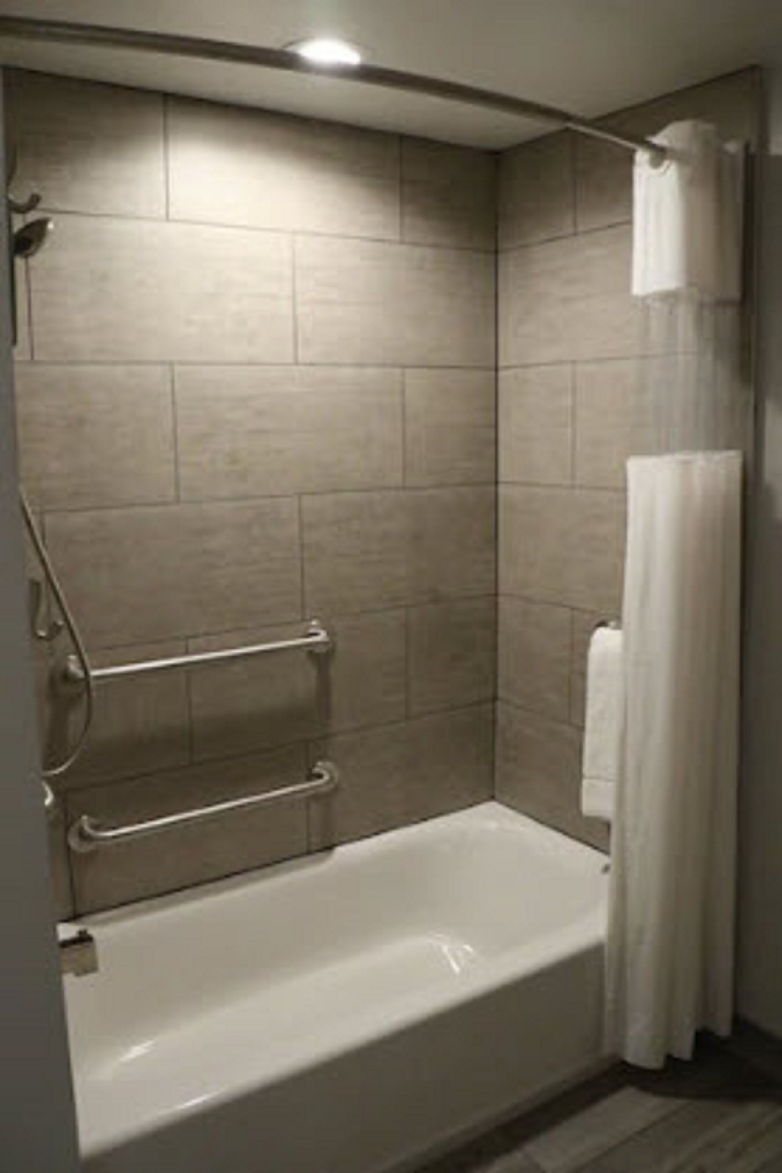 Un baño moderno con bañera, zona de ducha y un perchero para toallas.
