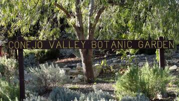 Señal del Jardín Botánico del Valle de Conejo rodeado de diversas plantas y árboles.
