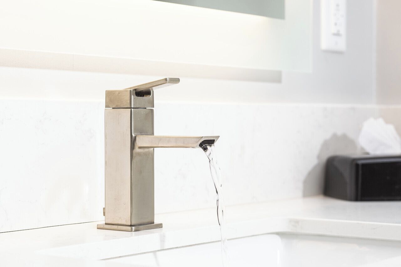 A modern bathroom with a stainless steel faucet and a white countertop.