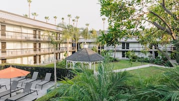 Un patio con un pabellón, sillas de descanso y una zona de piscina.