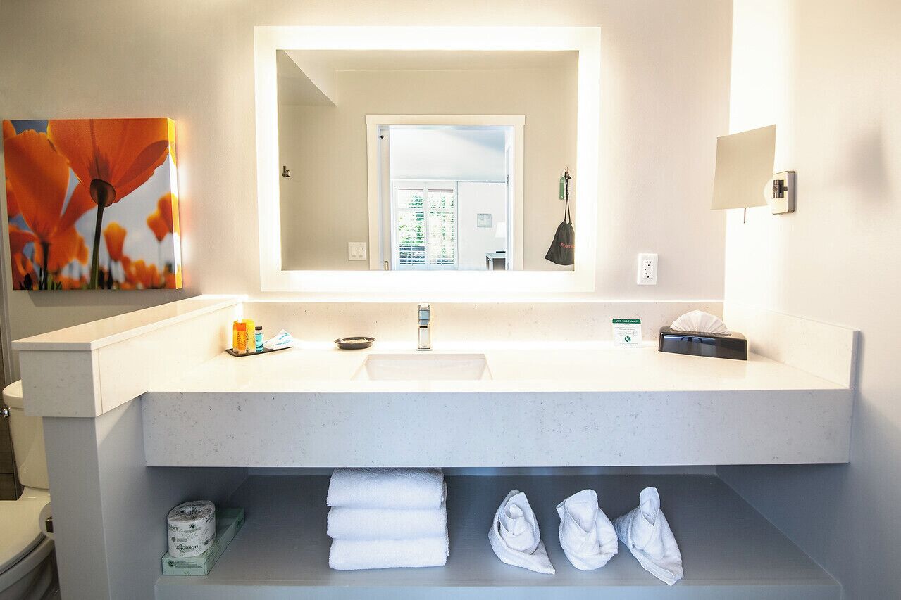 A modern bathroom with a white sink, a large mirror, and a towel rack.