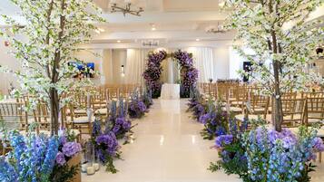 A wedding venue with a white aisle, floral decorations, and wooden chairs.