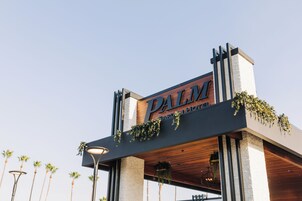 L’entrée d’un hôtel, avec une enseigne bien visible indiquant « PALM HOTEL ».