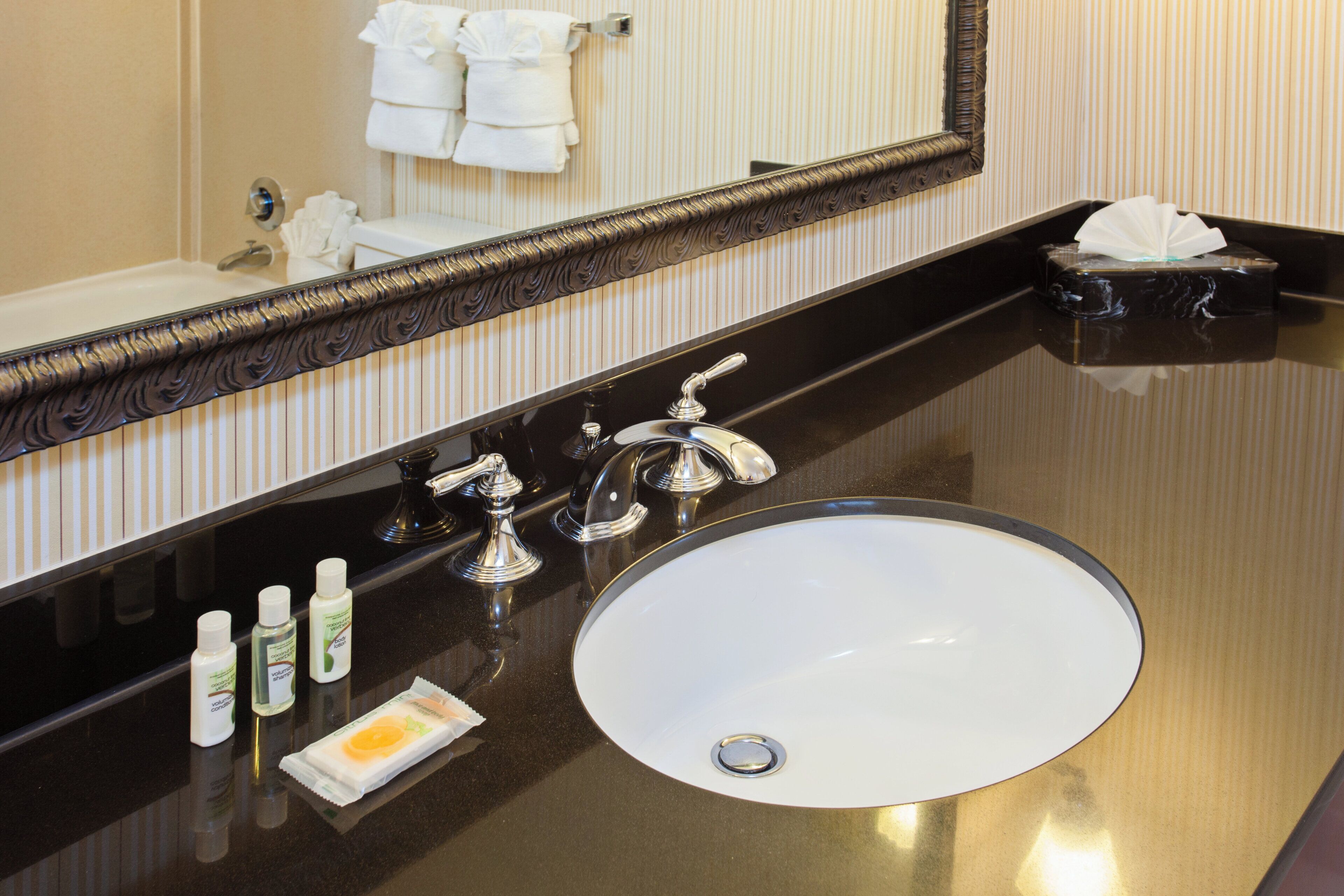 A bathroom with a large mirror, a sink, and toiletries on the counter.