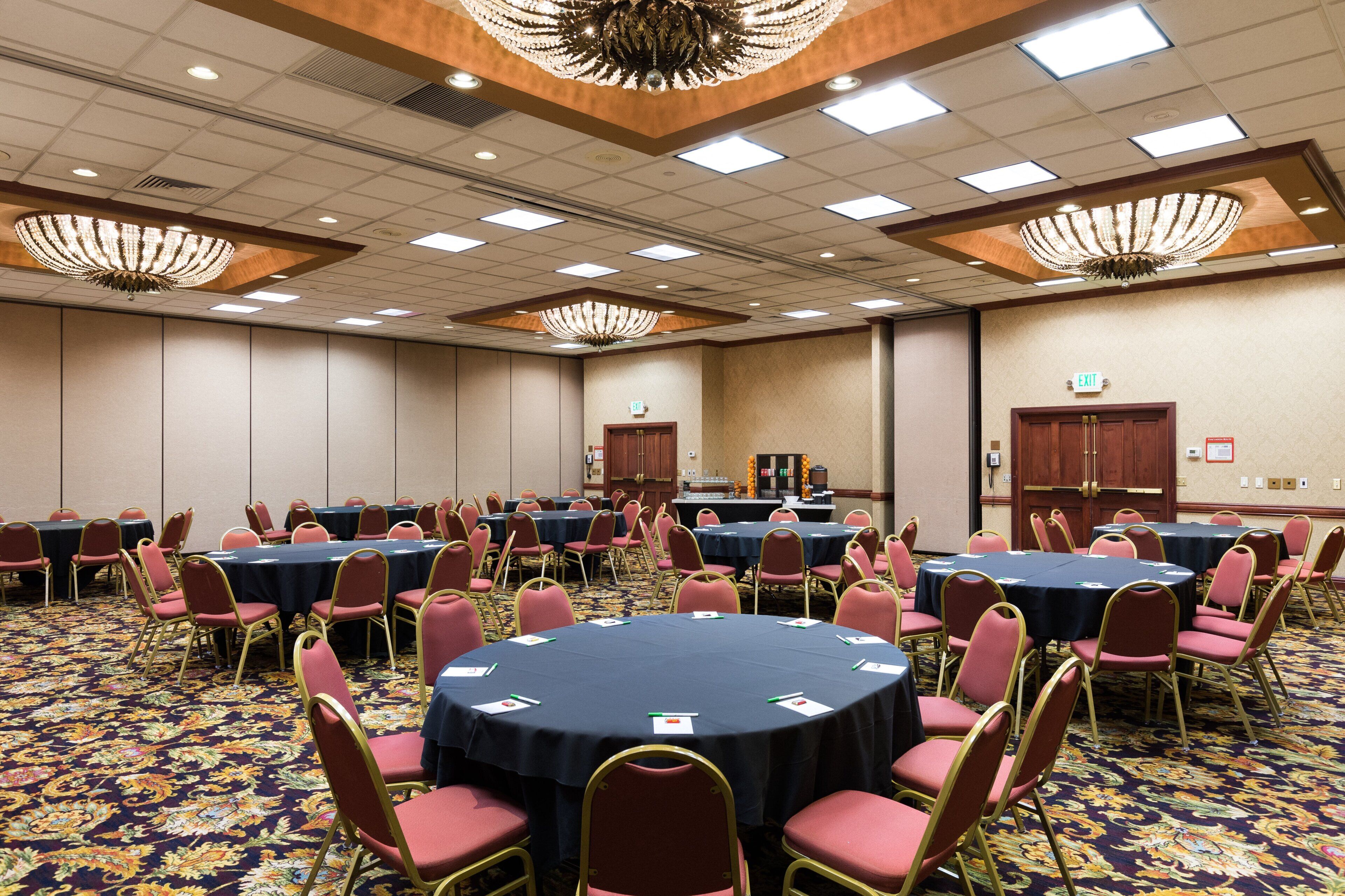 Une salle de conférence dotée de tables rondes et de chaises, ainsi que de plaques nominatives et de stylos.