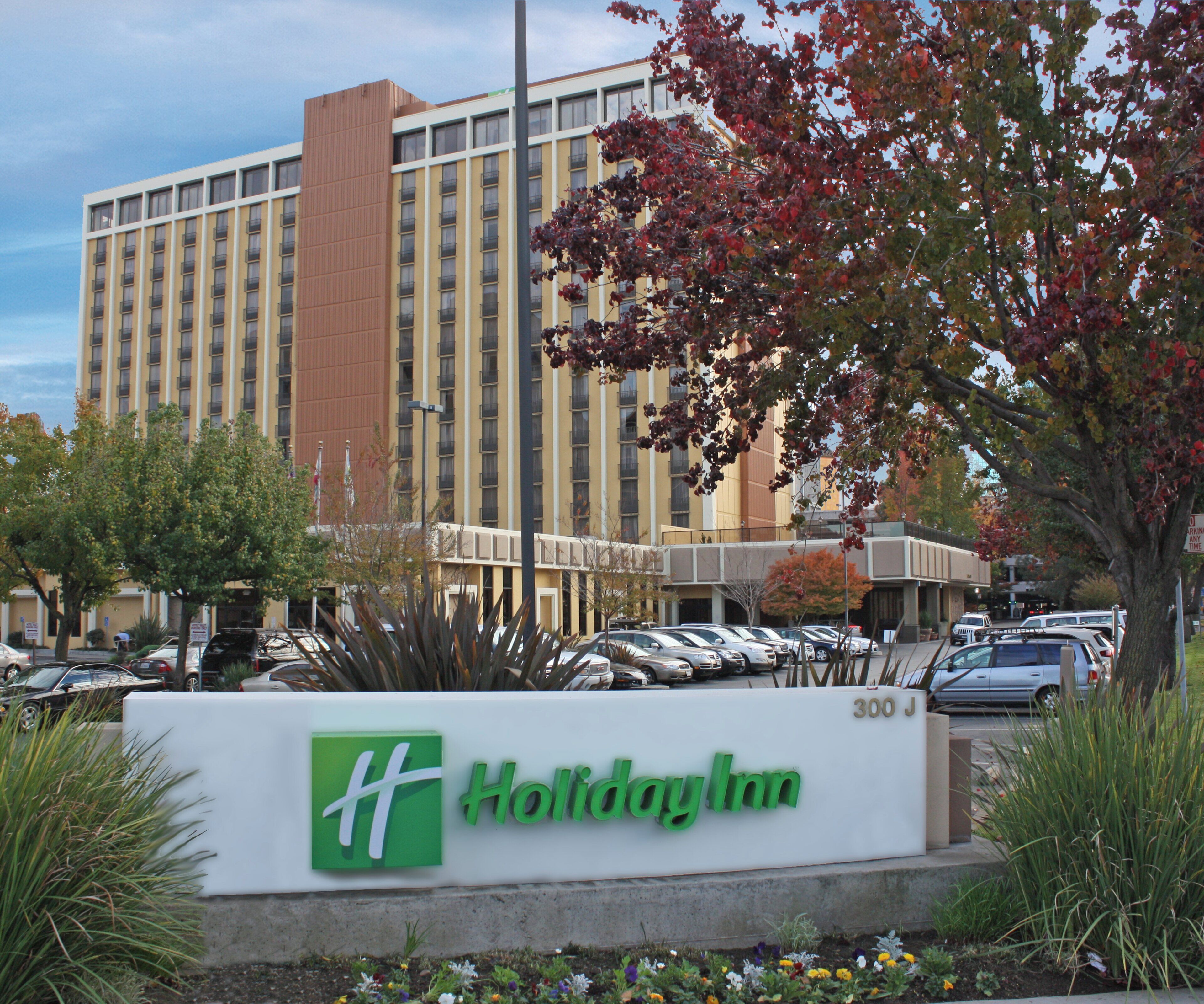 Une enseigne Holiday Inn, avec un parking et un immeuble à plusieurs étages en arrière-plan.