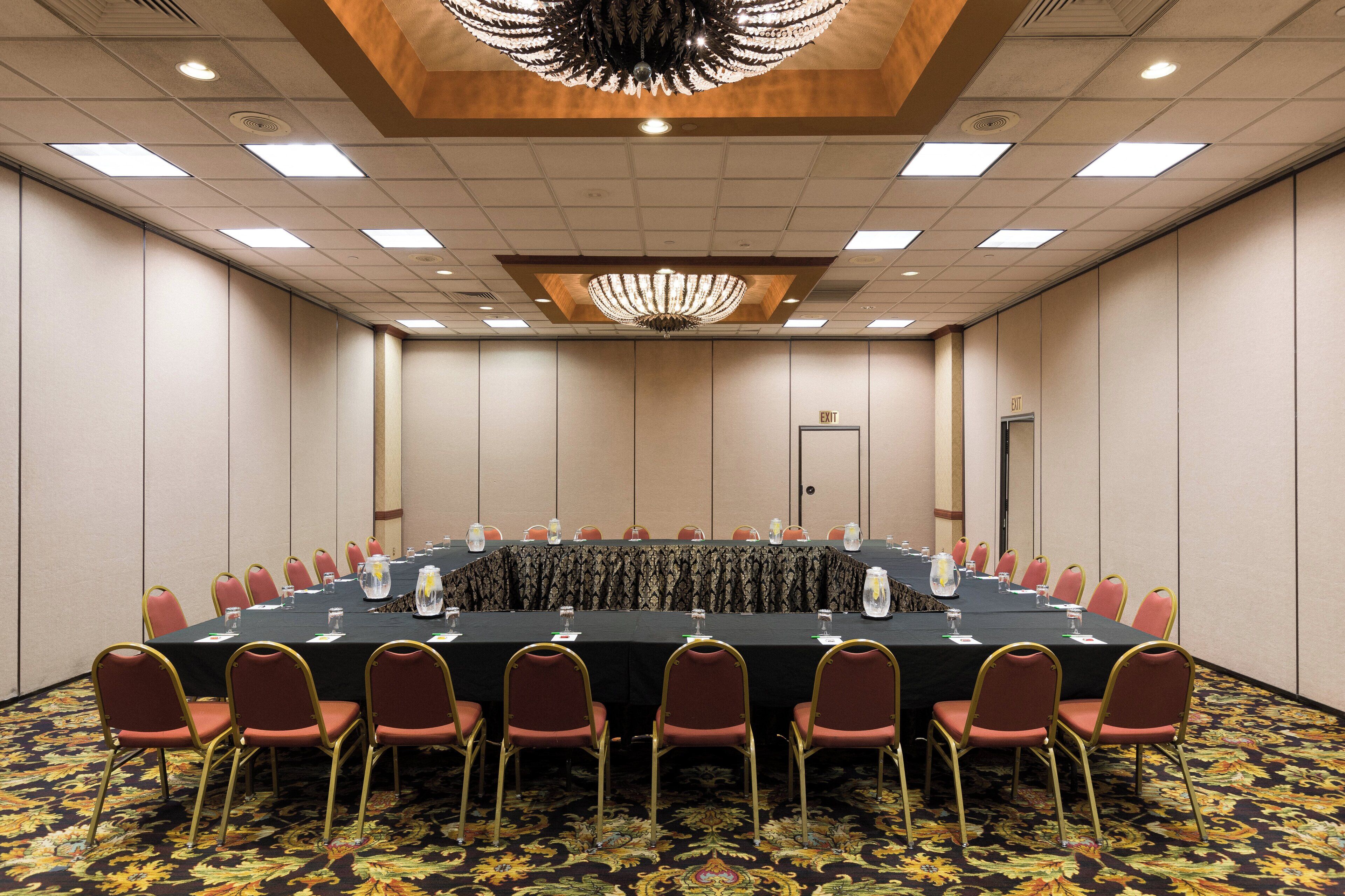 A conference room with a long table, red chairs, and a chandelier.