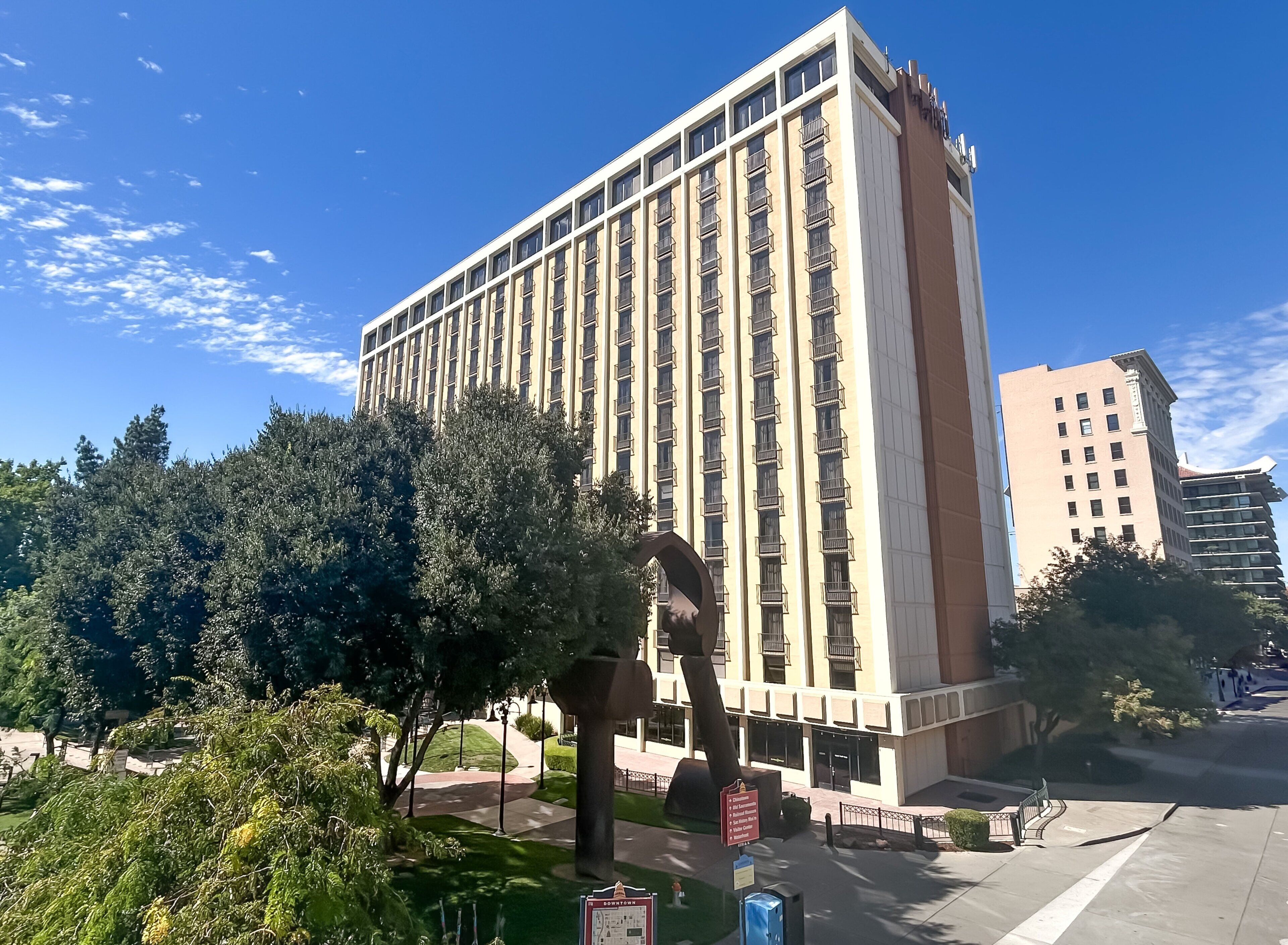 A tall, modern building with a beige facade and multiple balconies.