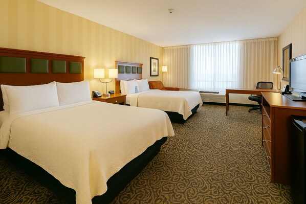 A hotel room with two beds, a desk, a television, and a window with curtains. - Holiday Inn Sacramento Downtown-Arena by IHG (Sacramento)