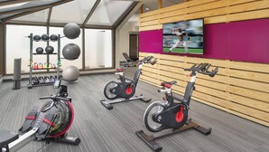 Un gimnasio con bicicletas estáticas, un televisor y pelotas de ejercicio.