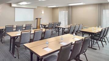 A conference room with multiple tables, chairs, a projector screen, and a podium.