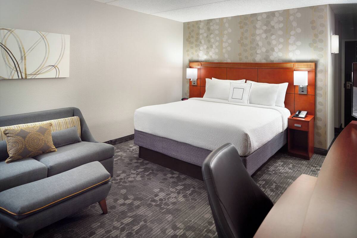 Una habitación de hotel con cama, sofá, escritorio y silla.