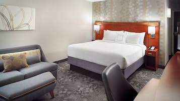 A hotel room with a bed, a sofa, a desk, and a chair.
