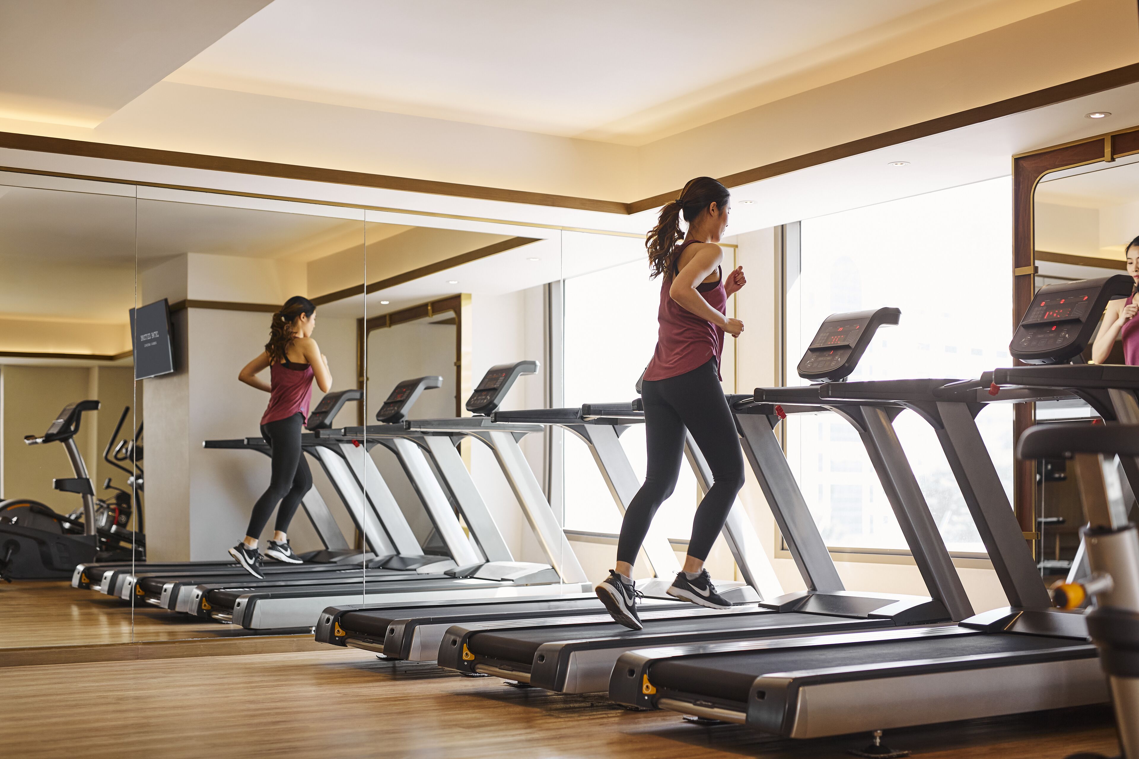 Un gimnasio con cintas de correr, un espejo y equipamiento de ejercicio.