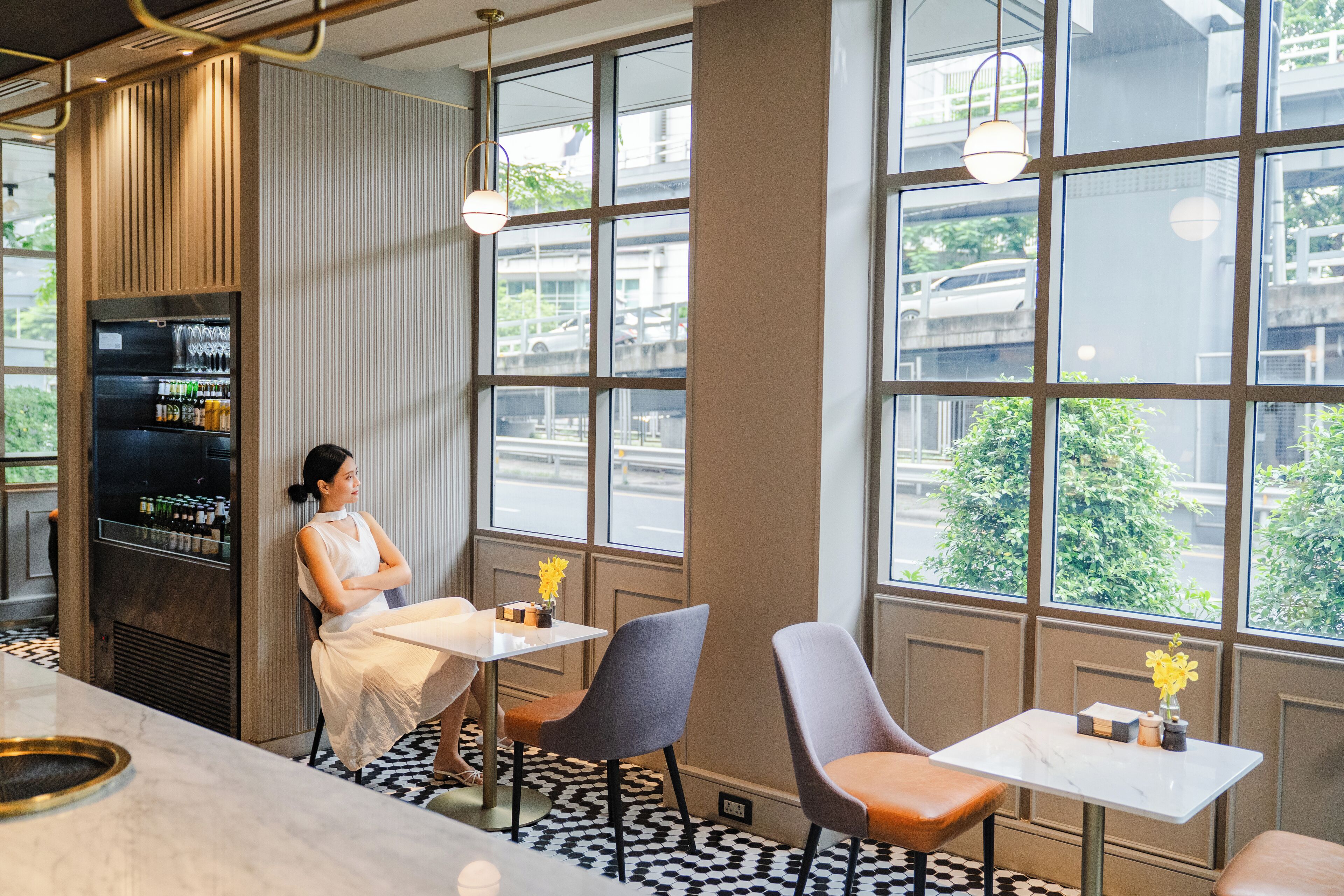 A modern interior with a bar area, seating, and large windows offering a view of the street.