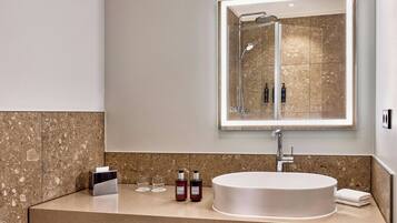 Een moderne badkamer met een rond wastafel, een grote spiegel en een douche.