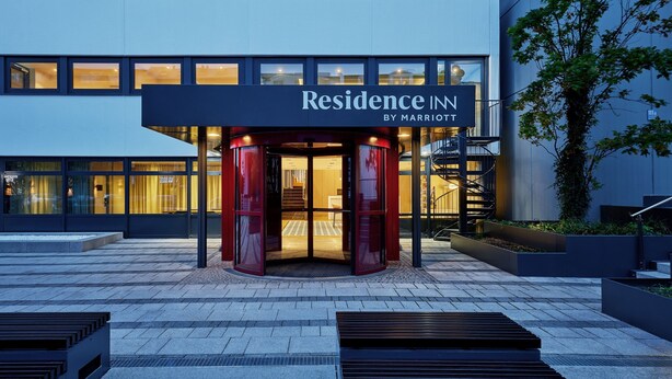 En moderne hotelindgang med en roterende dør, et skilt der siger "Residence Inn by Marriott", og en trappe, der fører til indgangen.