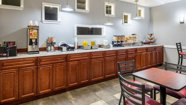 A hotel kitchen with wooden cabinets, a coffee station, and a breakfast bar. - Fulton Hotel - Oswego Riverfront (Fulton)